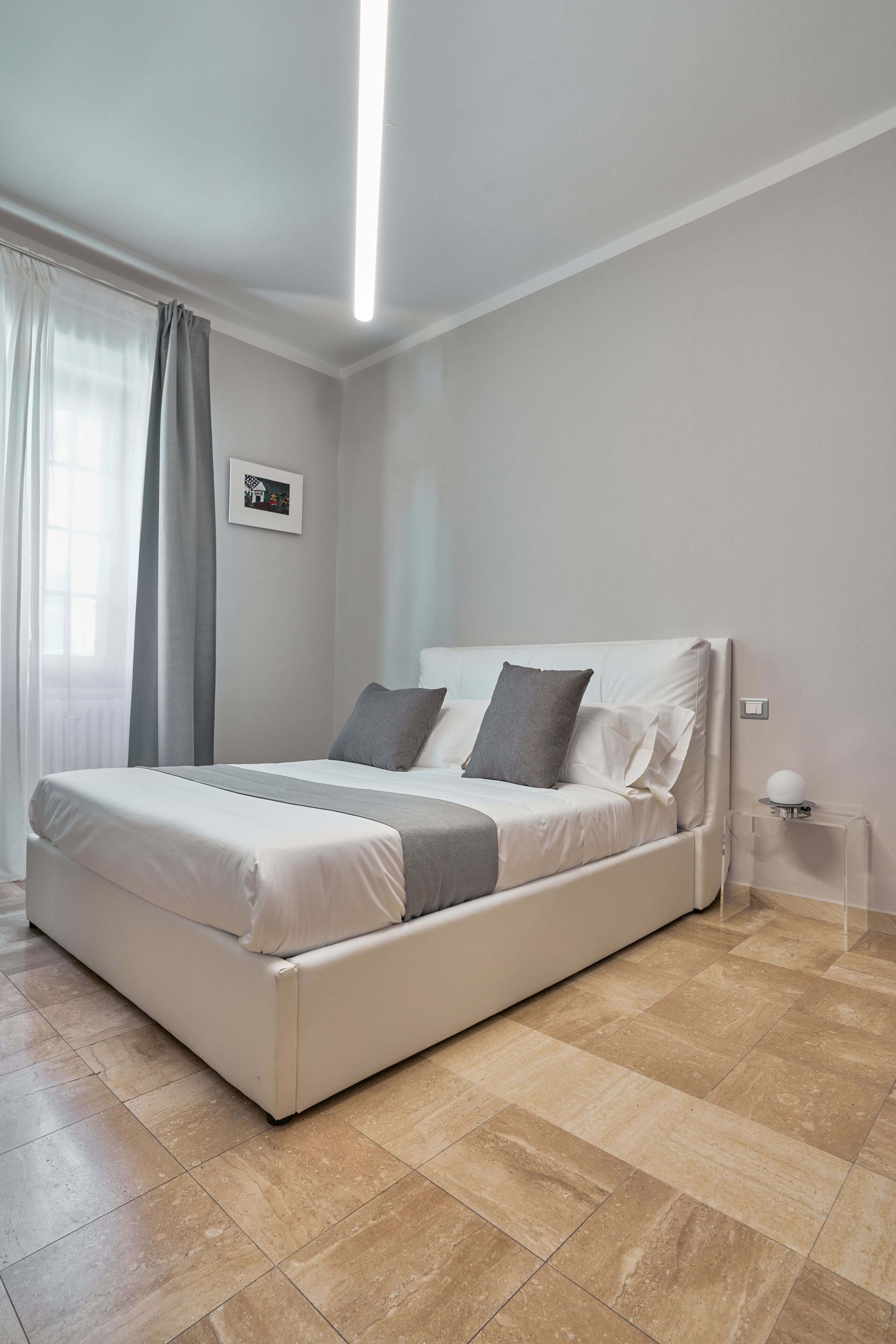 Un dormitorio moderno con una cama grande, una mesita de noche y un aplique de pared.