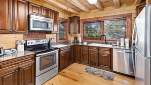 Uma cozinha moderna com armários de madeira, eletrodomésticos de aço inoxidável e uma grande janela com persianas.
