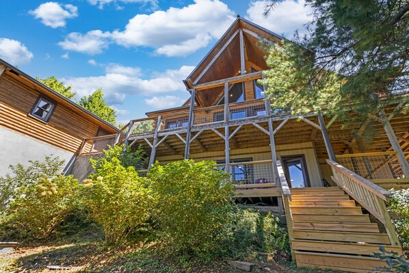 A wooden cabin with a balcony and a staircase leading to a second floor.