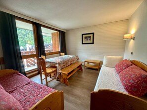 A cozy room with two beds, a table, and a bench.