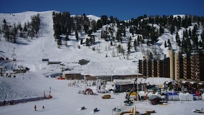 Ein Skigebiet mit Seilbahn, Gebäuden und einer Bergkulisse.