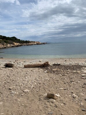 A rocky beach with clear water and a distant shoreline.