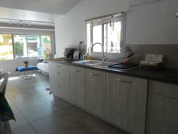 A modern kitchen with a large window, a sink, and a dining area with a table and chairs.