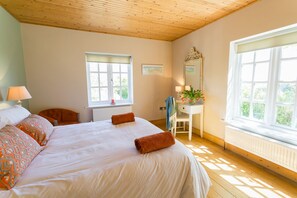 Comfortable bedroom with a neatly made bed, dresser, and table with a lamp.