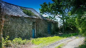 Rustic building surrounded by lush greenery, accessible via a gravel path.