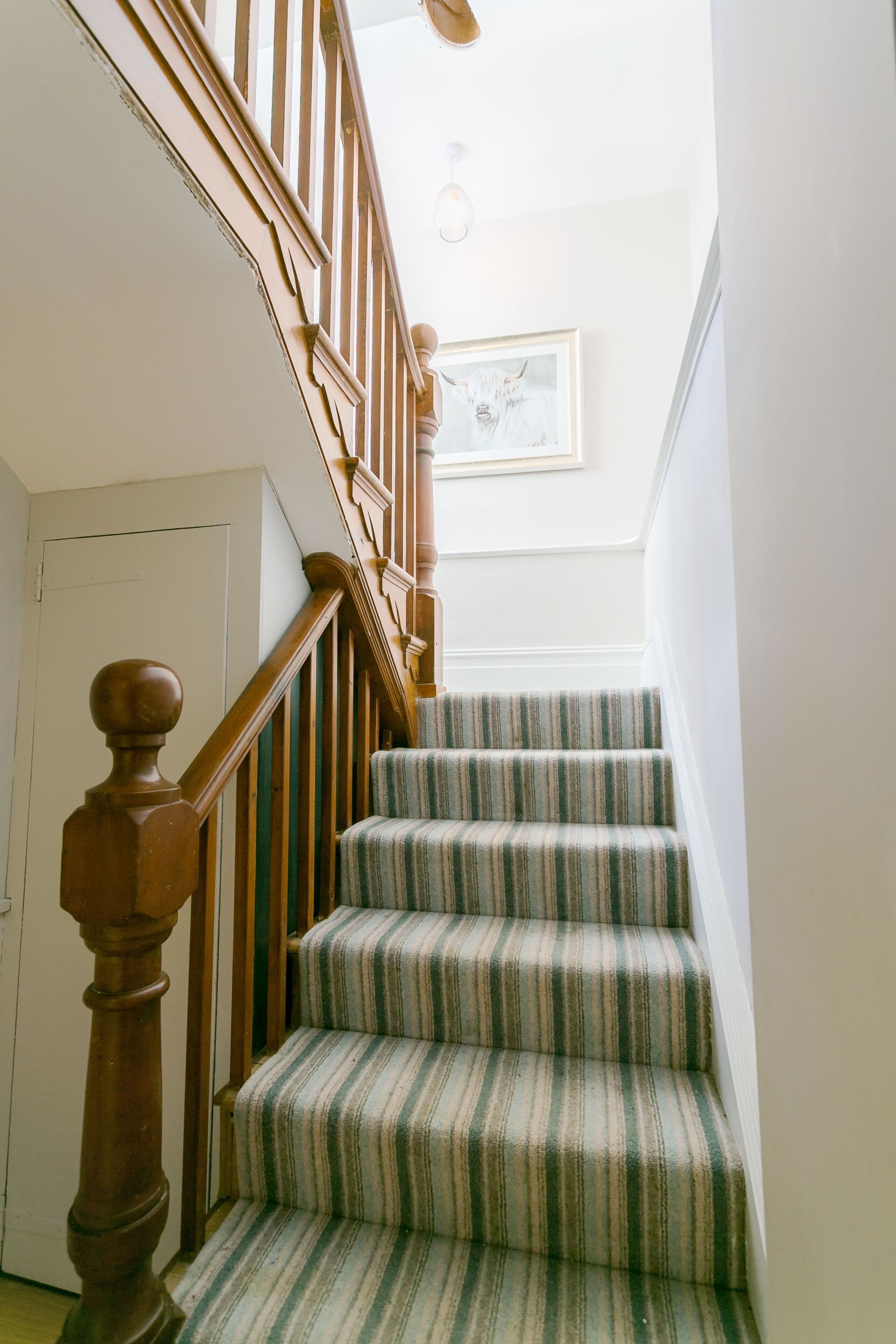 A staircase with wooden balusters and striped carpet.