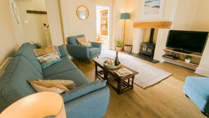 A cozy living room with a blue sofa, a matching armchair, a coffee table, a fireplace, and a television.