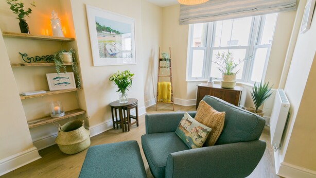 A cozy living room with a teal sofa, a small side table, and a ladder leaning against the wall.
