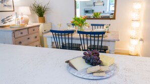 A dining area with a marble table, a plate of cheese and crackers, and a vase of flowers. - Ysgubor Wennol (Swallow Barn) -  a cosy fire that sleeps 4 guests  in 2 bedrooms (Llanfairpwll)