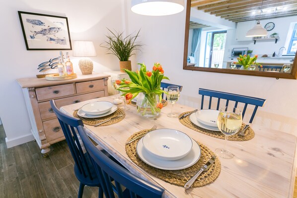 Mesa de jantar posta com pratos, talheres e um vaso de tulipas.