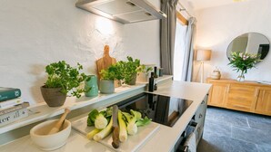 A kitchen with a white countertop, a wooden cutting board, fresh herbs, and a bowl. - Bryn Eithin -  a remote that sleeps 2 guests  in 1 bedroom (Bodorgan)