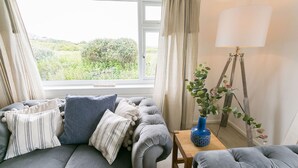 A cozy living room with a grey sofa, striped pillows, a blue vase, and a floor lamp. - Tideaway -  a coastal that sleeps 4 guests  in 2 bedrooms (Trearddur Bay)