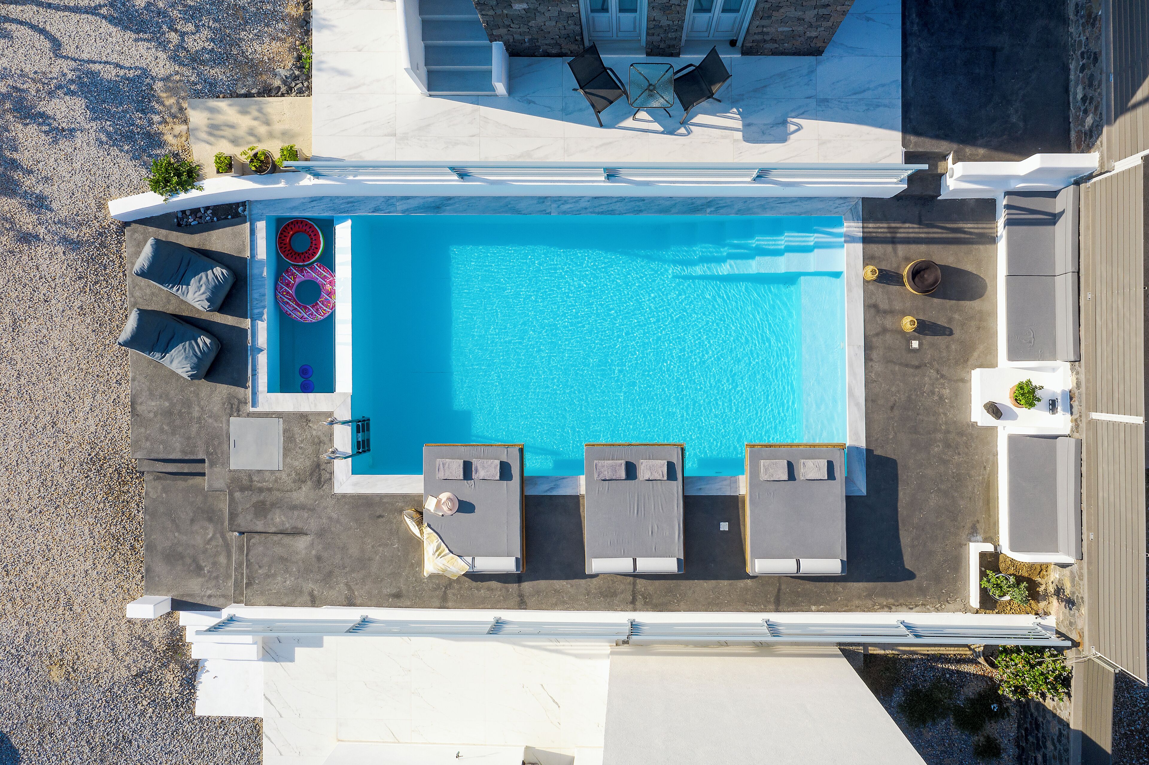 A rooftop pool area with lounge chairs, a table, and a small garden.