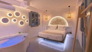 A modern bedroom with a large bed, a built-in bathtub, and unique wall lighting. - BlackStone Luxury Suites (Santorini)