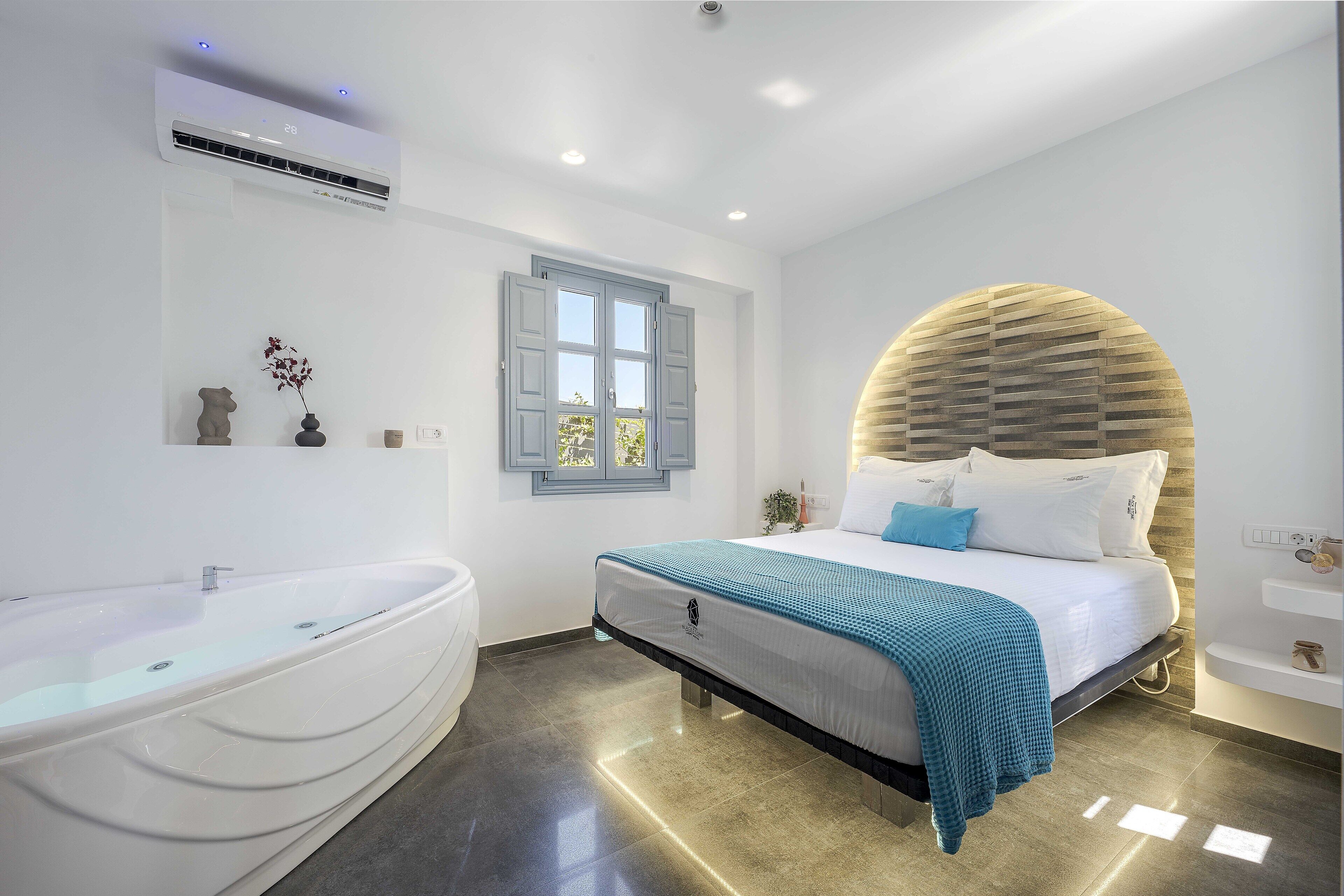 Un dormitorio moderno con una cama grande, una bañera y una ventana con contraventanas.