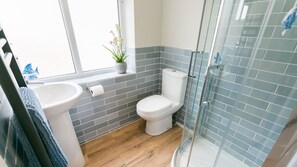 A bathroom with a toilet, sink, and a glass shower enclosure.