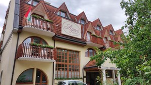 A building with a sign reading "Agnes Panzies." It features multiple balconies with wooden railings and flower boxes. - Ágnes Hotel (Hévíz)