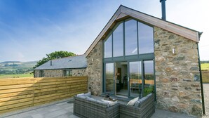 A stone building with a large glass door and a chimney. - Bwncath & Hebog -  a coastal that sleeps 8 guests  in 4 bedrooms (Llanfairynghornwy)