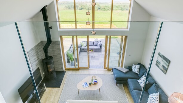 A modern living room with a glass ceiling, a fireplace, a sofa, and a coffee table. - Bwncath & Hebog -  a coastal that sleeps 8 guests  in 4 bedrooms (Llanfairynghornwy)
