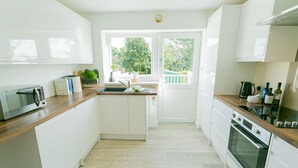 Une cuisine moderne avec des meubles blancs, un four encastré, un four à micro-ondes et un évier.