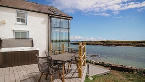 Une terrasse avec une table et des chaises, un jacuzzi et une vue sur la mer.