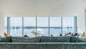 Un salon moderne doté d’une grande fenêtre donnant sur un plan d’eau et un pont.