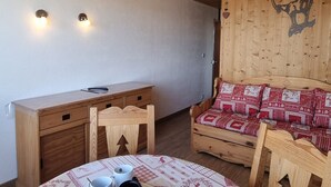 Et hyggeligt værelse med skrivebord i træ, et lille bord med kopper, en stribet sofa og en trævæg med dekorativ dyreskulptur.