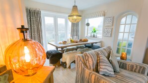 A cozy living room with a large wooden table, a sofa, and a hanging light fixture.