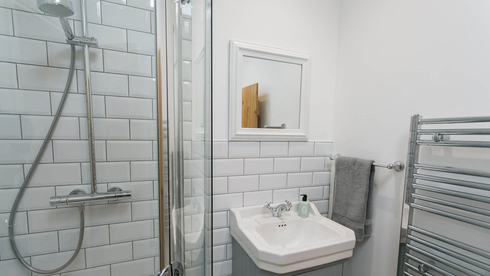 Un baño con cabina de ducha de vidrio, lavabo blanco y toallero.