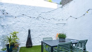 A patio with a table and chairs, string lights, and potted plants.