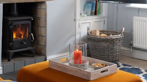 A cozy living room with a fireplace, a glass candle holder, and a tray with snacks. - Gwyndy -  a town that sleeps 4 guests  in 2 bedrooms (Beaumaris)