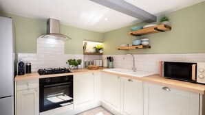 A modern kitchen with white cabinets, a built-in oven, a microwave, and a sink. - Gwyndy -  a town that sleeps 4 guests  in 2 bedrooms (Beaumaris)