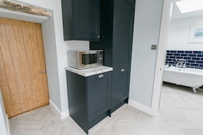 Bathroom features a microwave, dark cabinetry, and a white bathtub with claw feet.