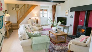 A cozy living room with a sofa, armchairs, a coffee table, and a fireplace. - Ty Gwair -  a cosy fire that sleeps 4 guests  in 2 bedrooms (Pentraeth)