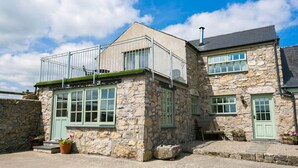 A stone building with a balcony and multiple windows. - Ty Gwair -  a cosy fire that sleeps 4 guests  in 2 bedrooms (Pentraeth)