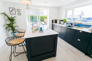 Uma cozinha moderna com uma ilha grande, banquetas e vista para o exterior.