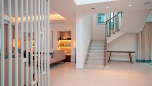 Un intérieur moderne avec un escalier, un canapé et une étagère décorative.