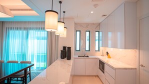 Une cuisine moderne dotée d’un plan de travail en marbre, de meubles blancs et de luminaires suspendus.