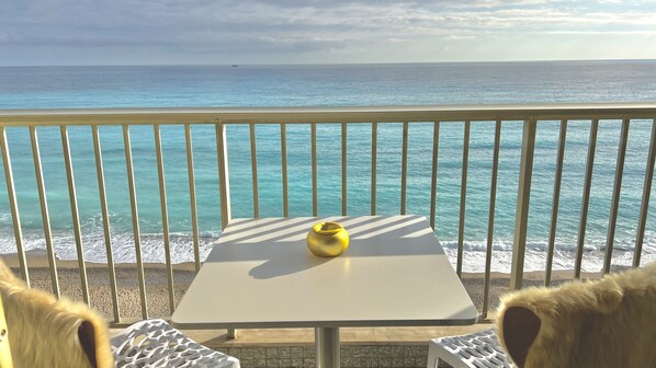 Un balcón con mesa y sillas, con vistas a una playa y al mar.