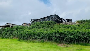 A modern building with a flat roof and a satellite dish, surrounded by lush greenery.