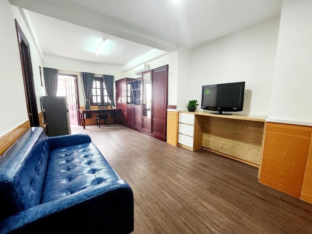 A room with a blue sofa, a television on a wooden stand, and a wooden cabinet.