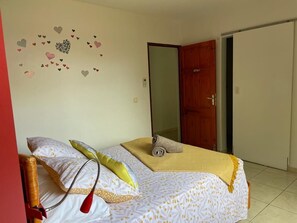 Un dormitorio con cama, almohadas, una colcha y una decoración de corazones en la pared.