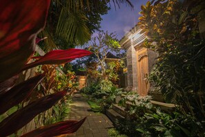 A garden pathway leading to a traditional building with stone steps and a wooden door. - The Dayuh Ubud (Ubud)