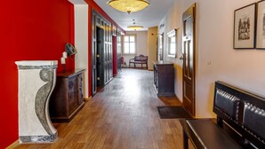 A hallway with wooden flooring, a marble column, a bench, and a red wall. - Watzdorfer Geleitschenke und Herberge (Weimar)