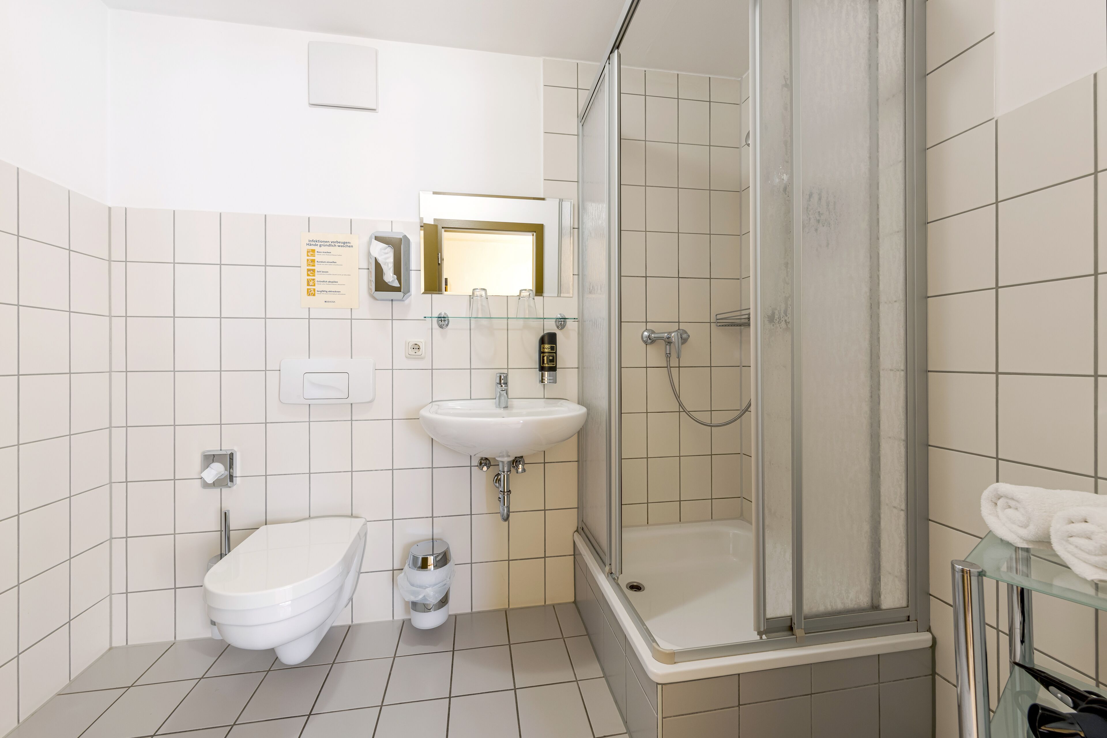 Une salle de bain moderne équipée de toilettes, d’un lavabo et d’une douche à parois de verre.