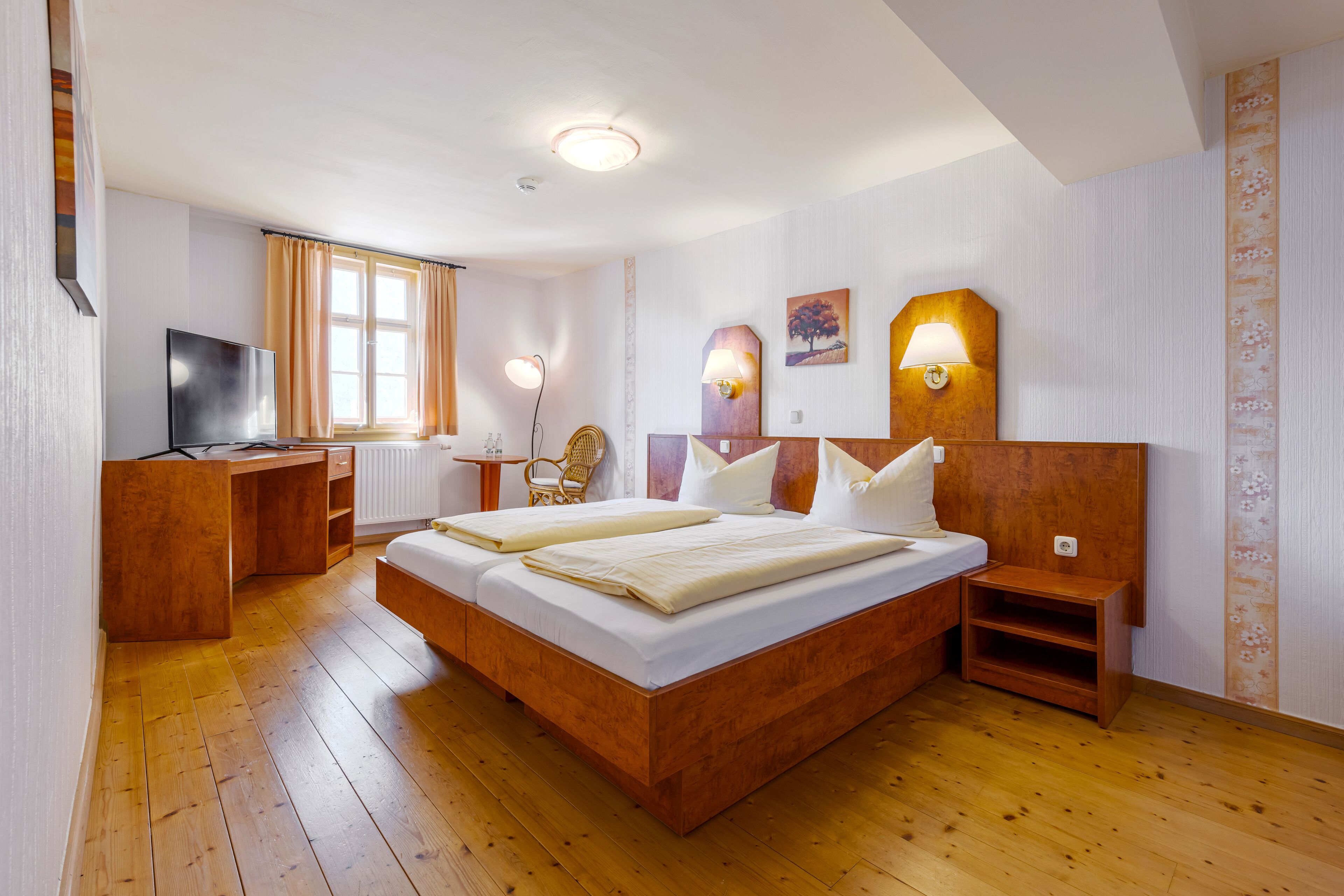 Un dormitorio con una cama de madera, un escritorio, una silla y un televisor.