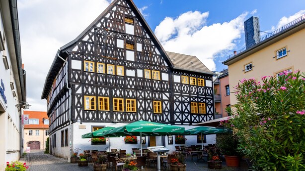 A traditional half-timbered building with a courtyard featuring outdoor seating and potted plants. - Watzdorfer Geleitschenke und Herberge (Weimar)