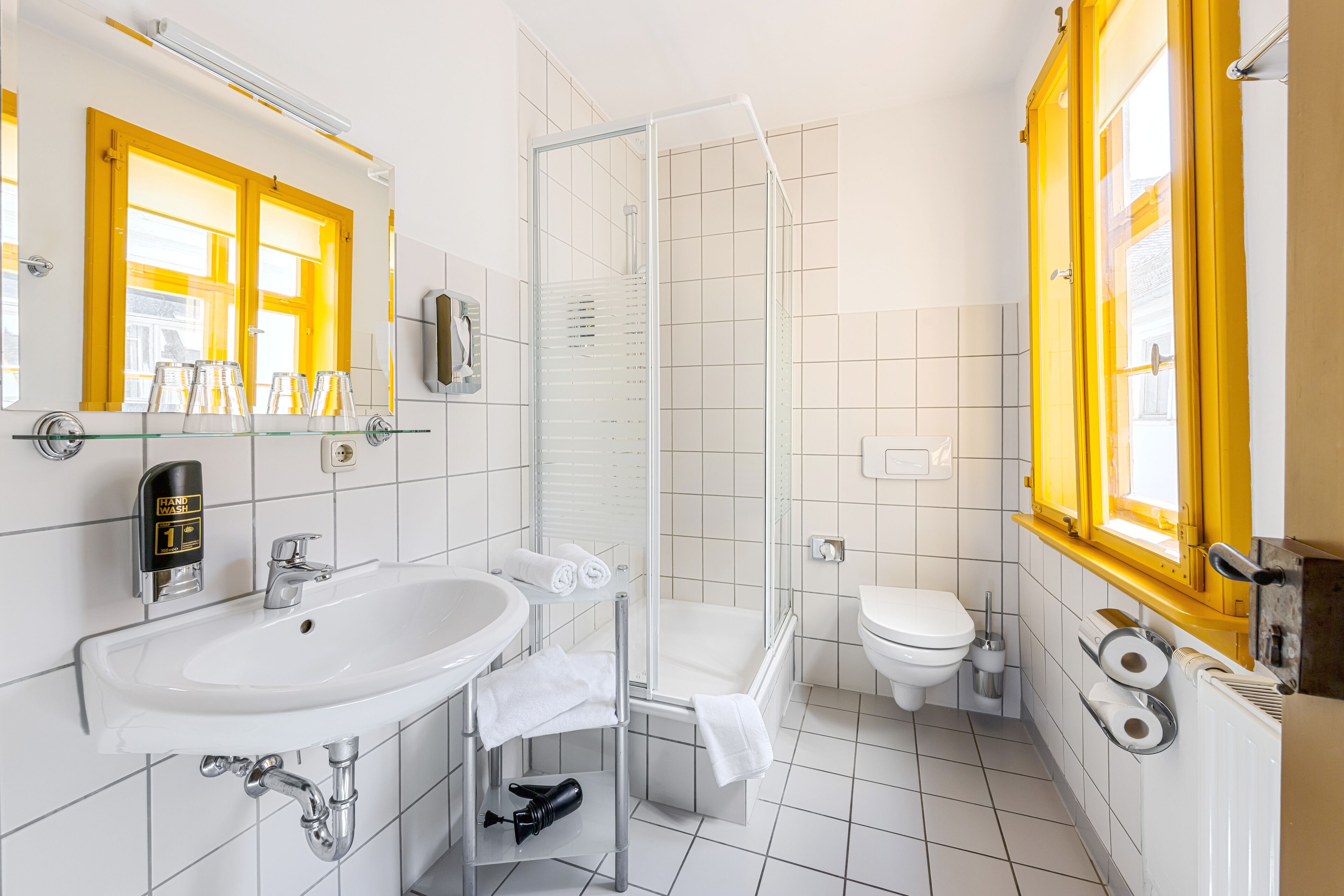 Un baño moderno con ducha de vidrio, un lavamanos blanco y un inodoro.