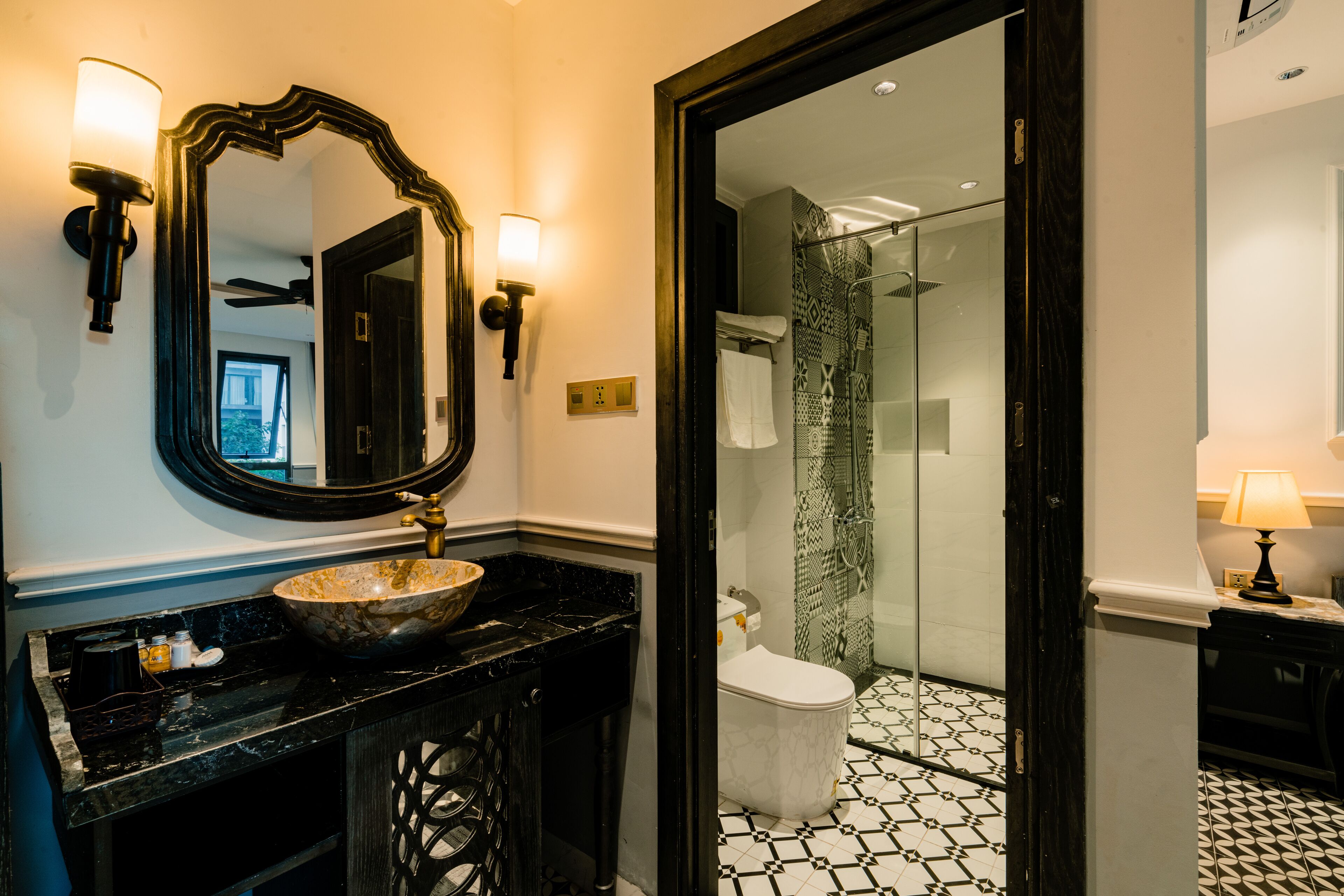 A bathroom with a black marble sink, a large mirror, and a glass shower enclosure.