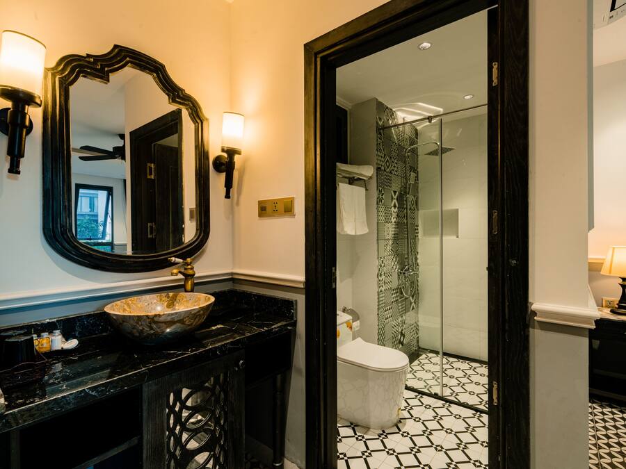 A bathroom with a black marble sink, a large mirror, and a glass shower enclosure.
